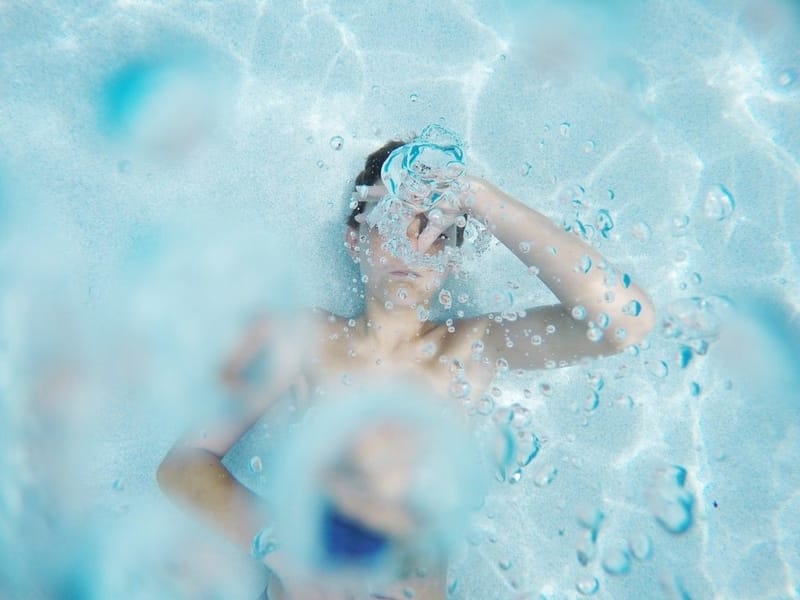 Child in swimming pool holding breath under water