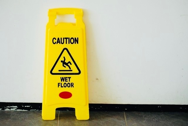 Caution sign indicating a wet floor and slippery surface to help prevent someone from falling.